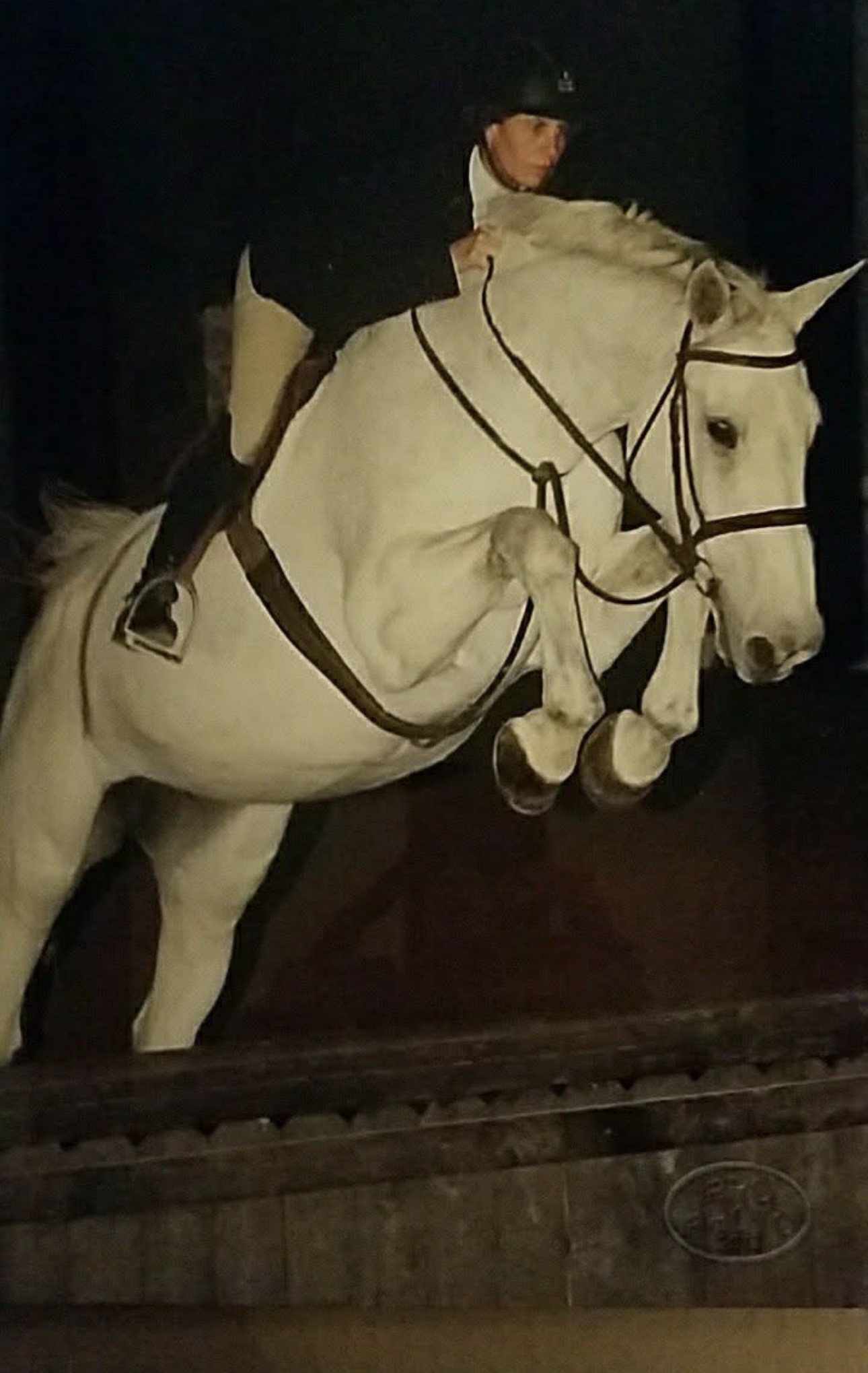 Allison Wicks riding a white horse over a jump